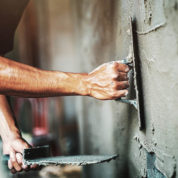 Worker plastering cement on wall - building materials
