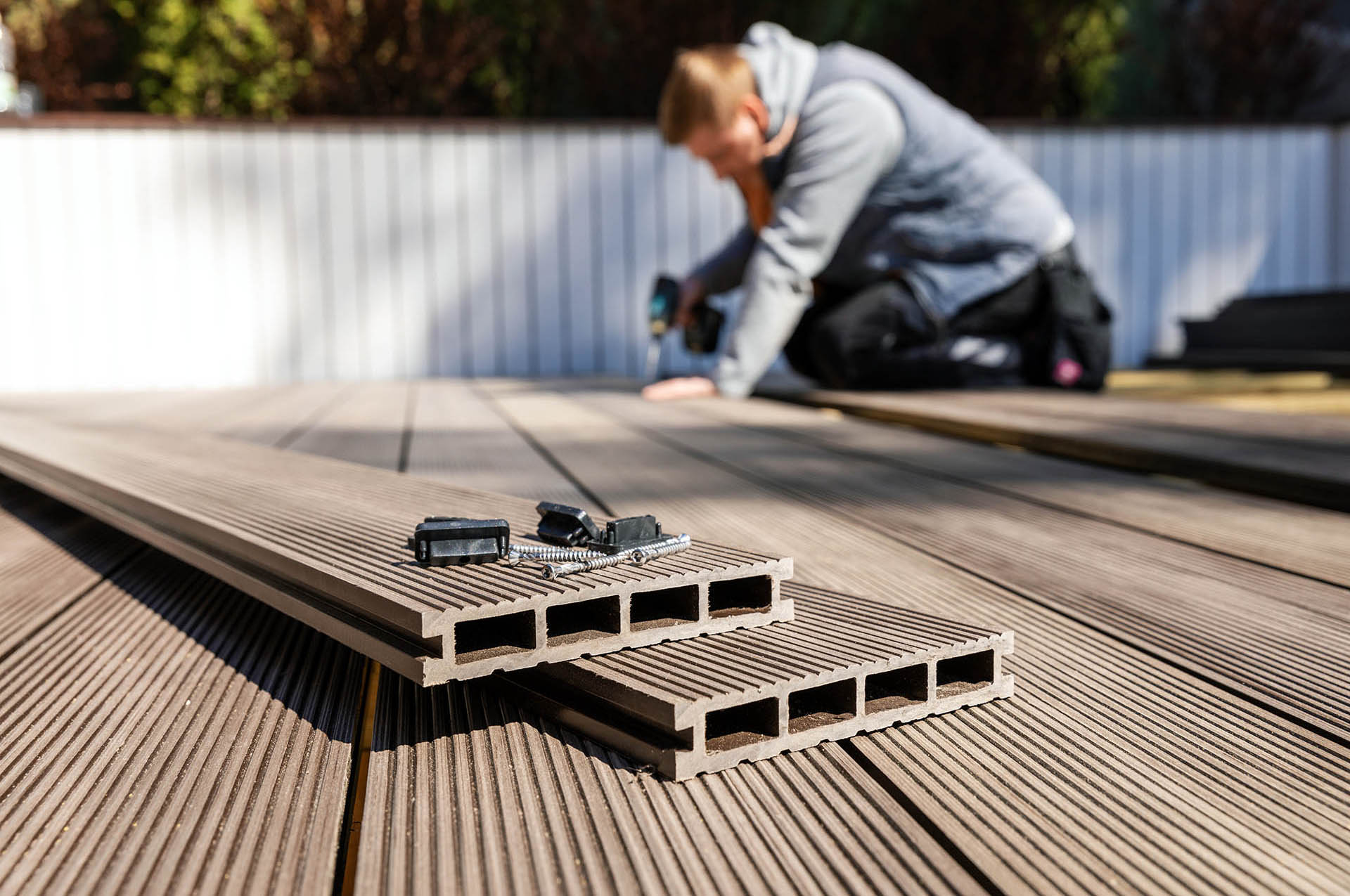 Worker installing wood plastic Cladco composite decking boards - composites alternatives