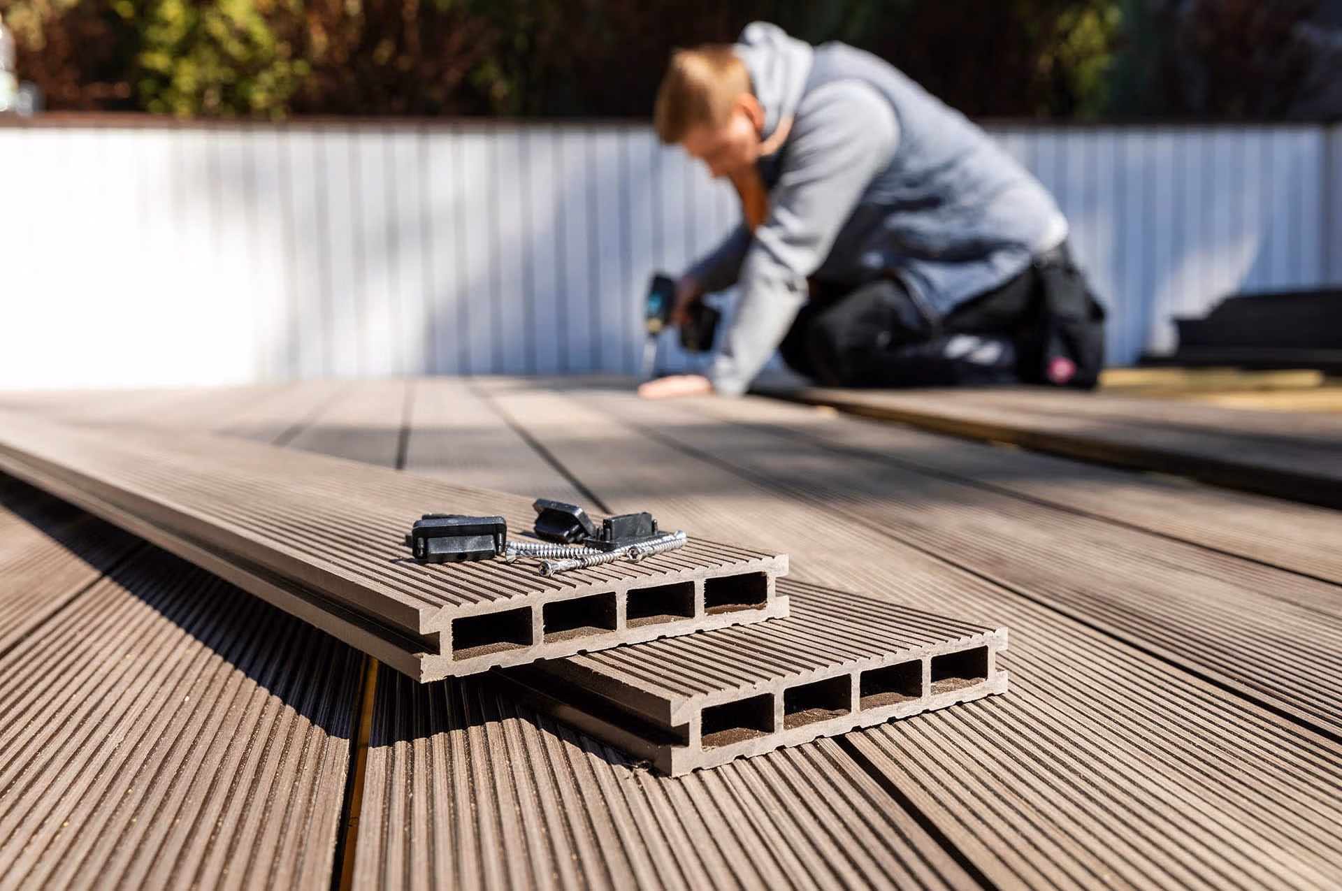 Worker installing wood plastic Cladco composite decking boards - composites alternatives